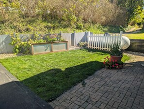 A well-maintained garden with a paved walkway, a wooden fence, and various potted plants. - Dogs Stay Free! Fenced Lakefront House with Deck (Delton)