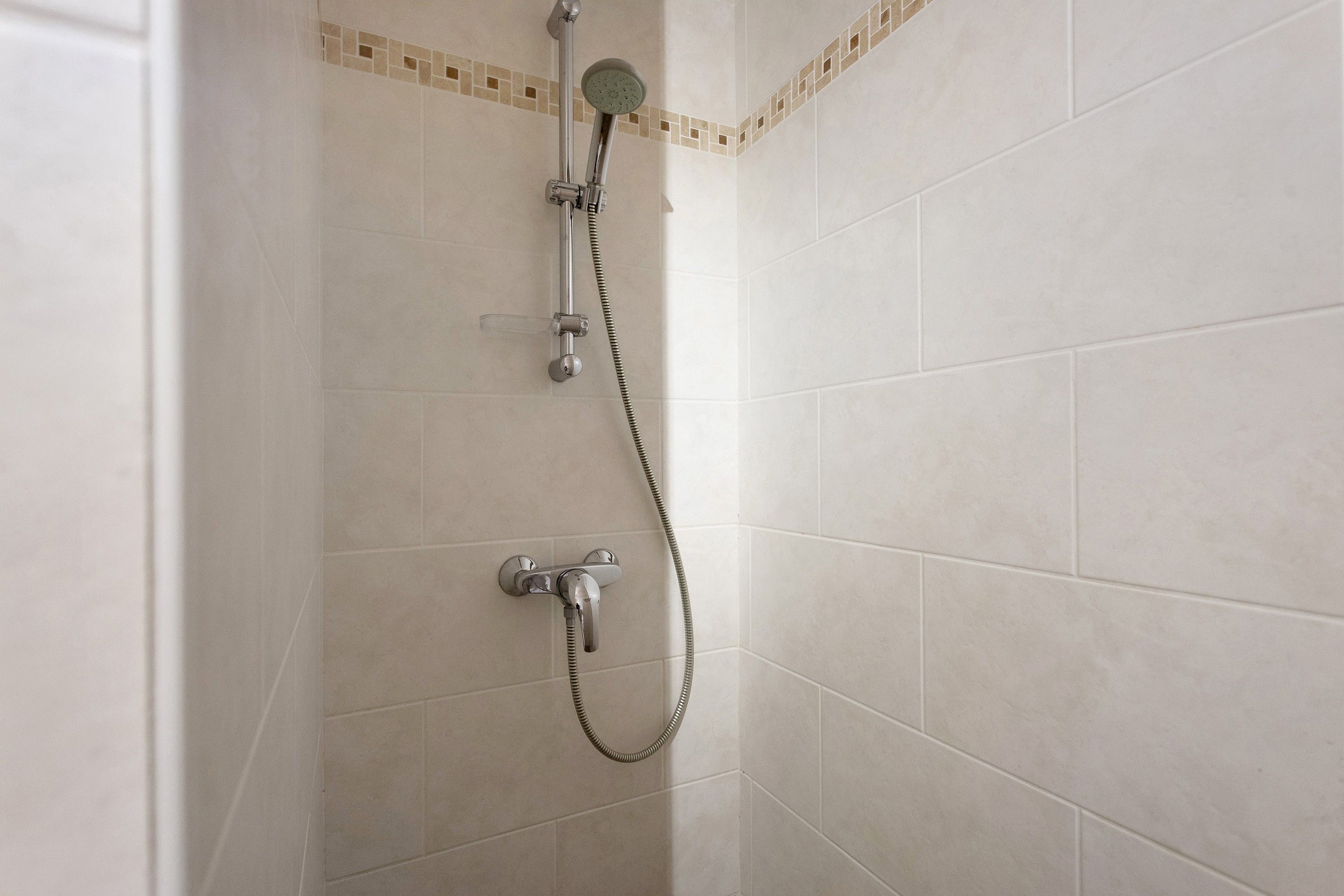 Eine Dusche mit Handbrause und Wandarmatur.