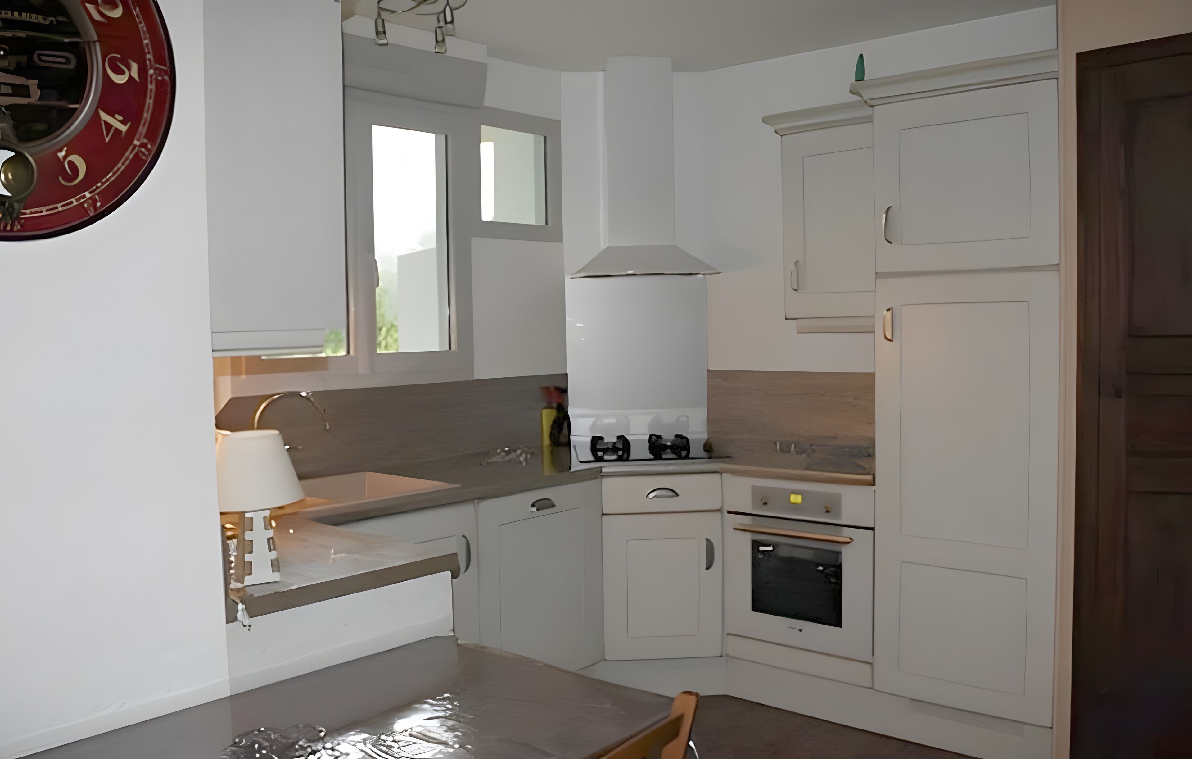 Een keuken met witte kasten, een fornuis, een gootsteen en een raam.