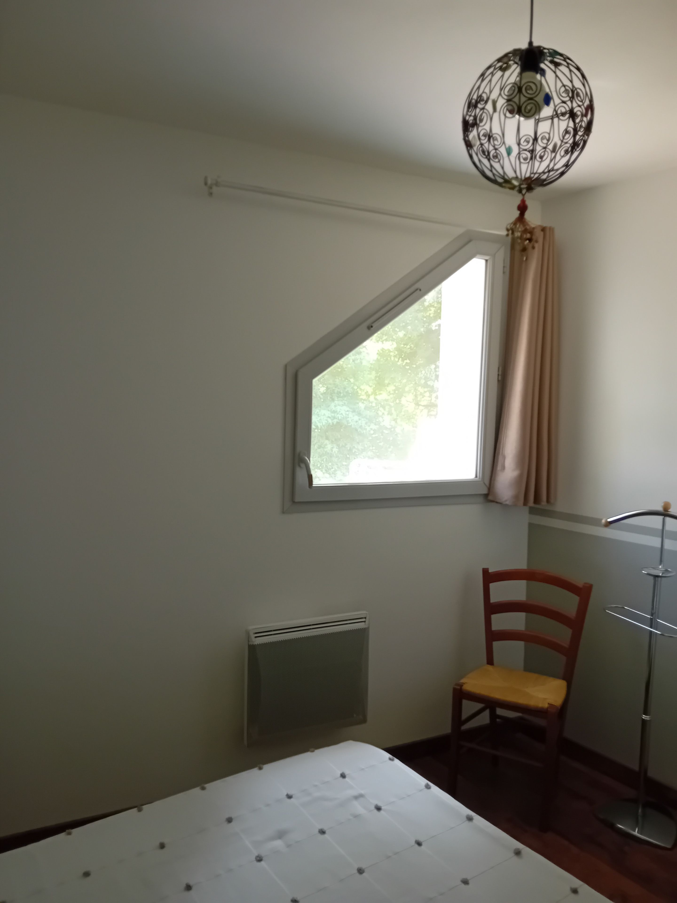 Een kamer met raam, een radiator, een stoel en een tafel.