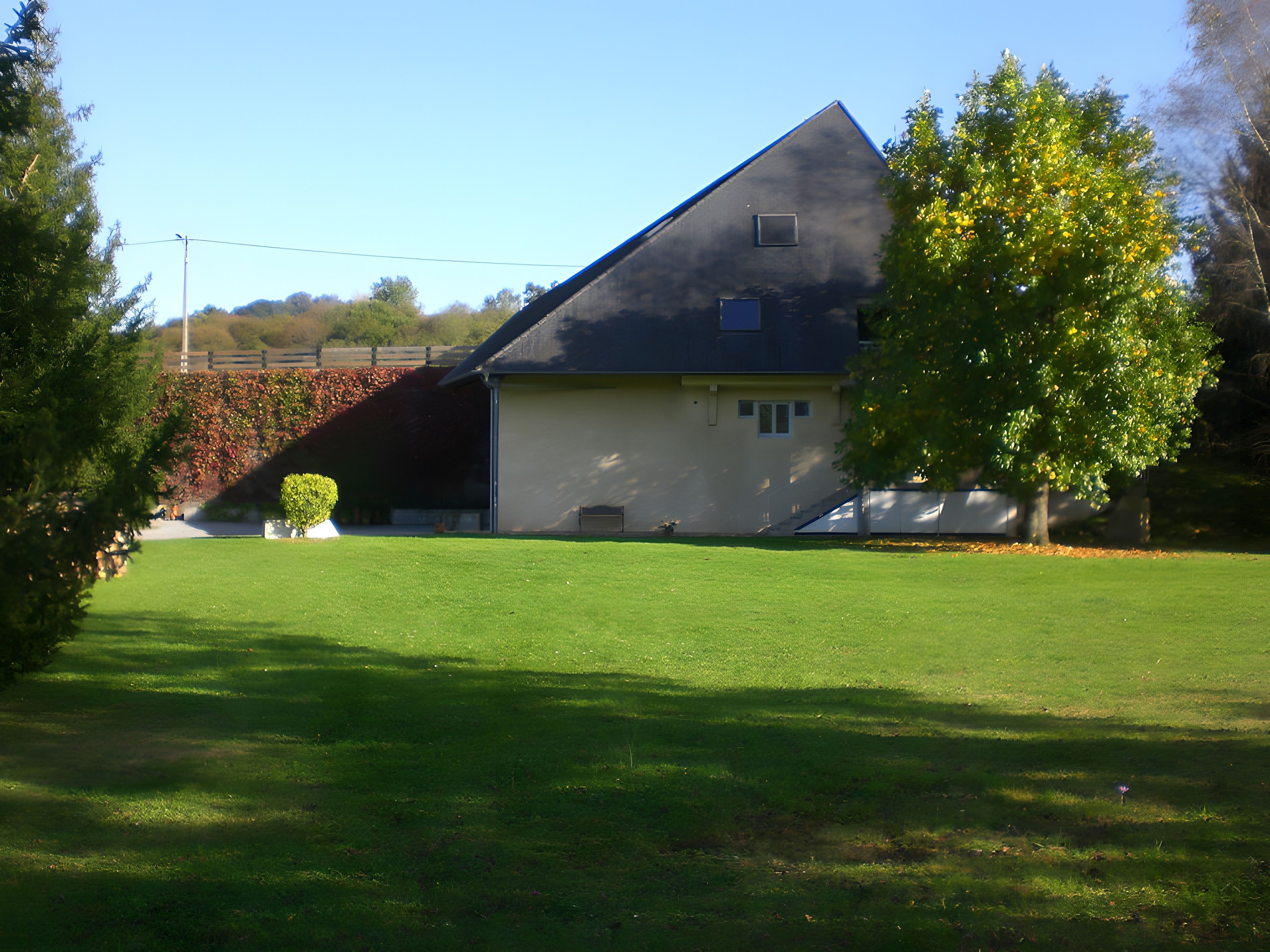 Une maison de plain-pied avec un toit en pente, un petit porche à l’avant et une pelouse bien entretenue.