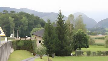 A rural landscape with a house, a pathway, and a mountain in the background.