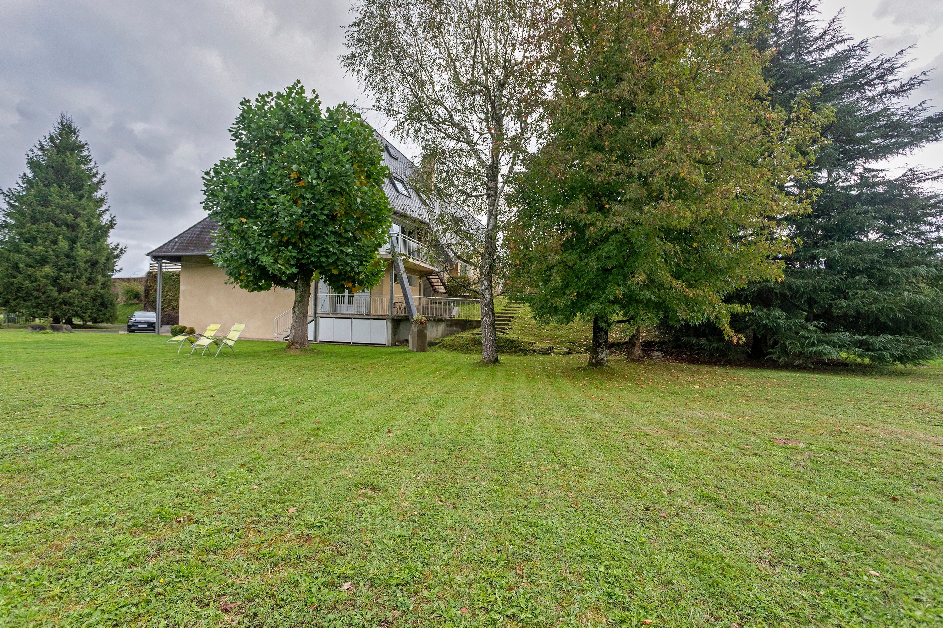 A residential property with a house, a lawn, and a tree.