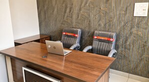 A conference room with a wooden table, two leather chairs, and an HP laptop.
