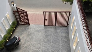A gated driveway leading to a building with a motorbike parked on the left.