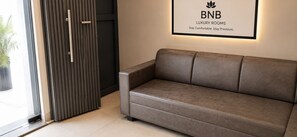 Un interior moderno con un sofá de cuero, un letrero enmarcado encima y una puerta con líneas verticales.