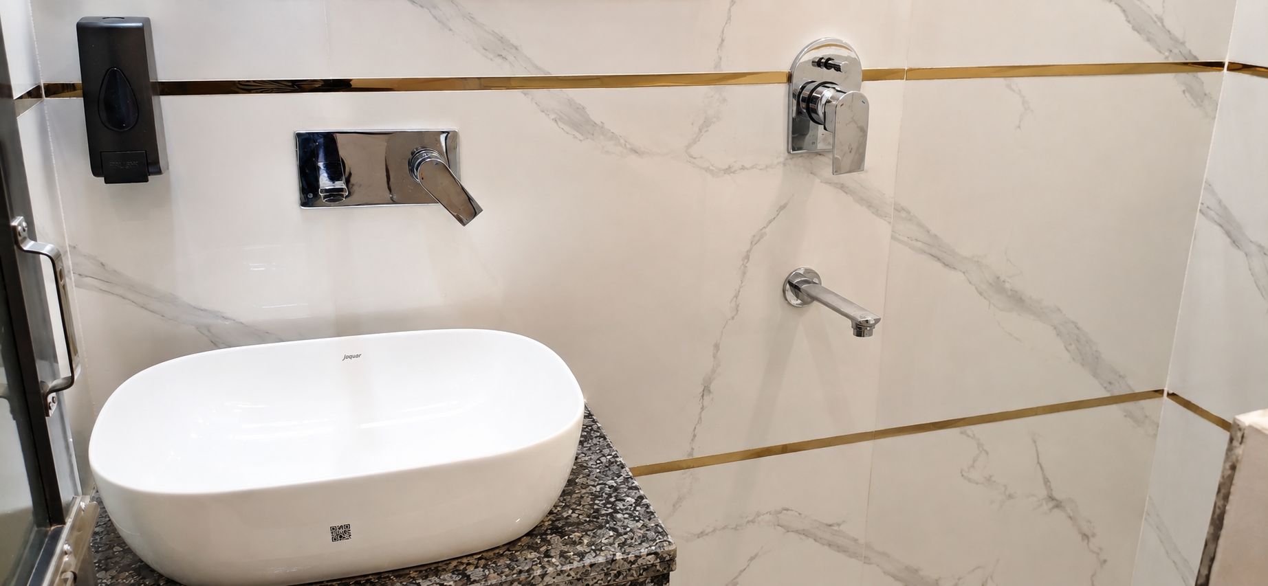 Un baño con un lavamanos blanco, un cabezal de ducha de mano y un grifo empotrado en la pared.