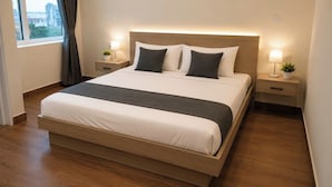 Una habitación de hotel moderna con una cama grande, mesitas de noche con lámparas y vistas a la ciudad por la ventana.