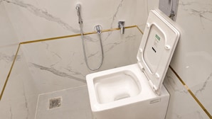 Un baño moderno con inodoro, ducha y piso de mármol.