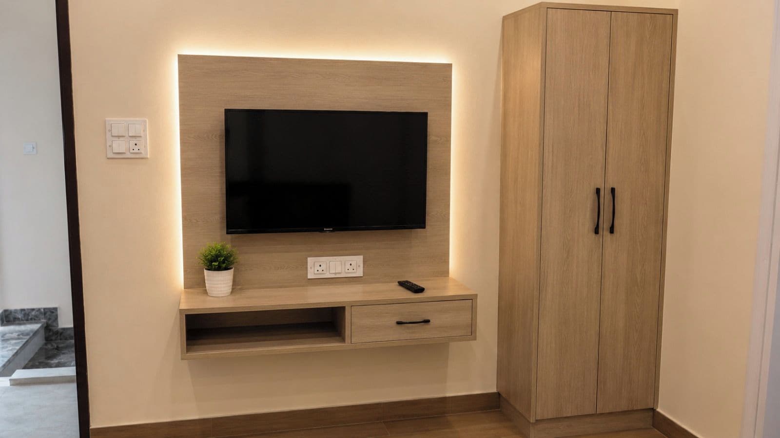 Un mobile TV moderno con una TV a schermo piatto, una piccola pianta e un telecomando.