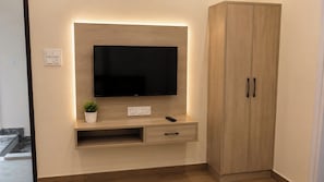 A modern entertainment unit with a flat-screen TV, a small plant, and a remote control.