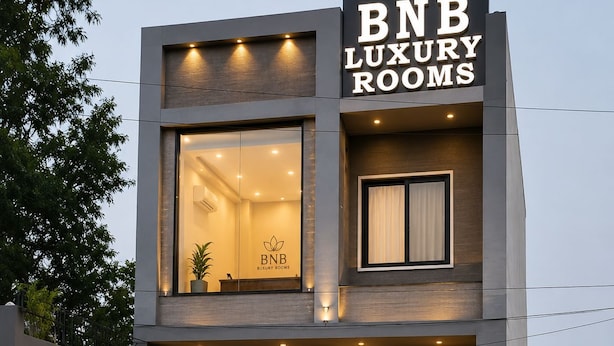 Un edificio moderno con un letrero que dice BNB Luxury Rooms, con un coche estacionado adelante.