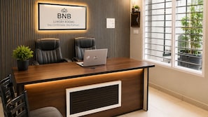 Una recepción con dos sillones de cuero, una computadora portátil y un letrero que dice 'BNB LUXURY ROOMS Stay Comfortable. Stay Premium'.