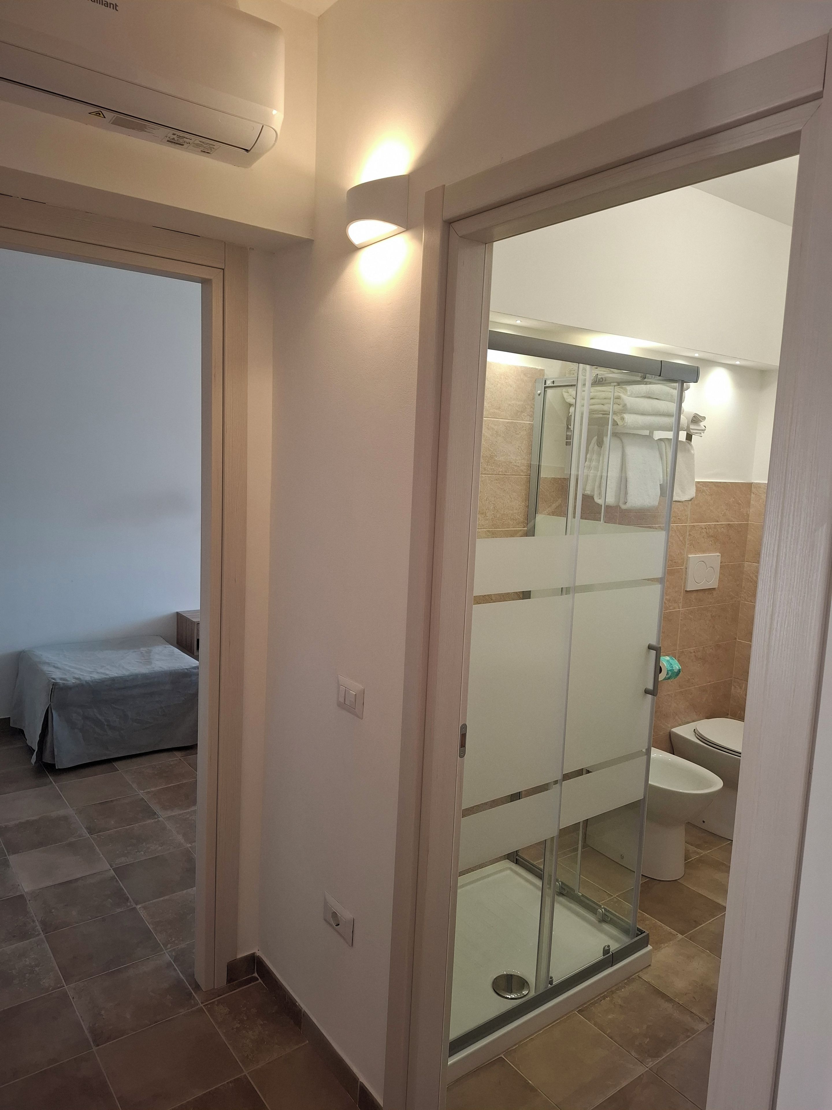 Een badkamer met een douchecabine van glas, een toilet en een wastafel.