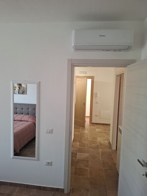 Un passadís amb un llit, una porta i un aparell d'aire condicionat.
