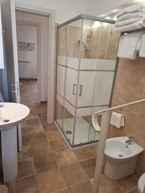 Un bany amb dutxa de vidre, un vàter i un lavabo.