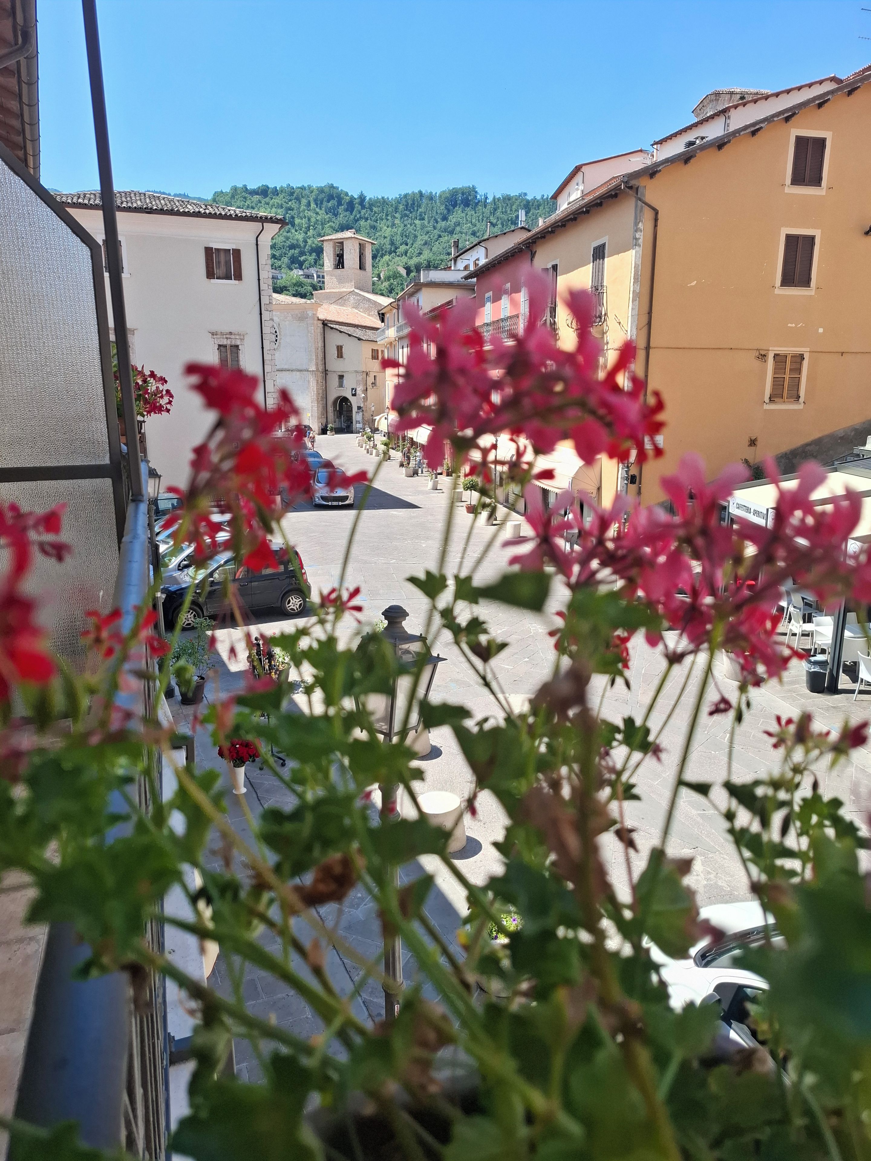 Une vue de rue avec des immeubles, des voitures garées et un ciel dégagé.