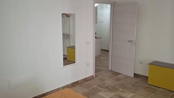 Une chambre à coucher comprenant un lit, une armoire, un miroir et une porte donnant sur une autre pièce.
