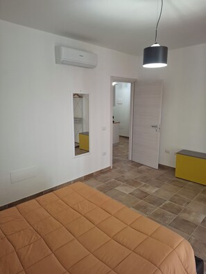 Un dormitori amb un llit, un armari, un mirall i una porta que dona a una altra habitació.