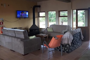 A living room with a sofa, a chair, a television, and a fireplace. - Pousada do Pampa  (Jaguarão)
