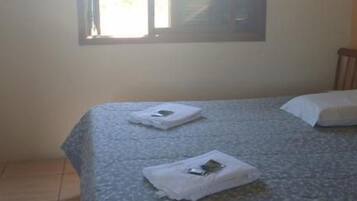 Ein Zimmer mit einem Bett, einem Fenster mit Jalousien und einer Klimaanlage.
