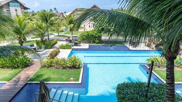 A swimming pool with multiple lanes, surrounded by palm trees and a grassy area.