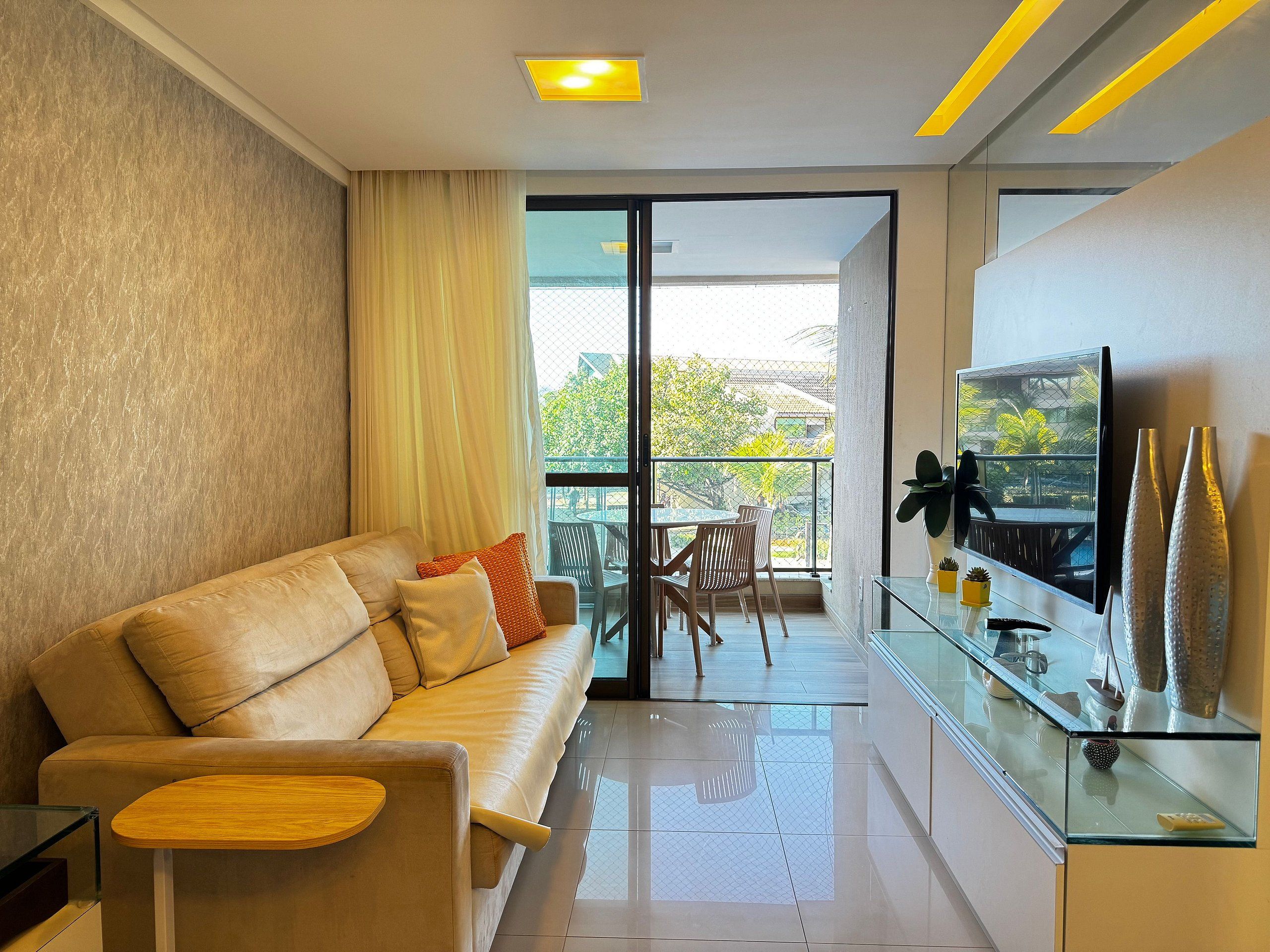 Una sala de estar moderna con un sofá, una mesa de centro de vidrio y un televisor en un mueble de vidrio.