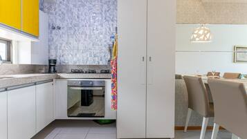 A modern kitchen with a gas stove, oven, and white cabinets.