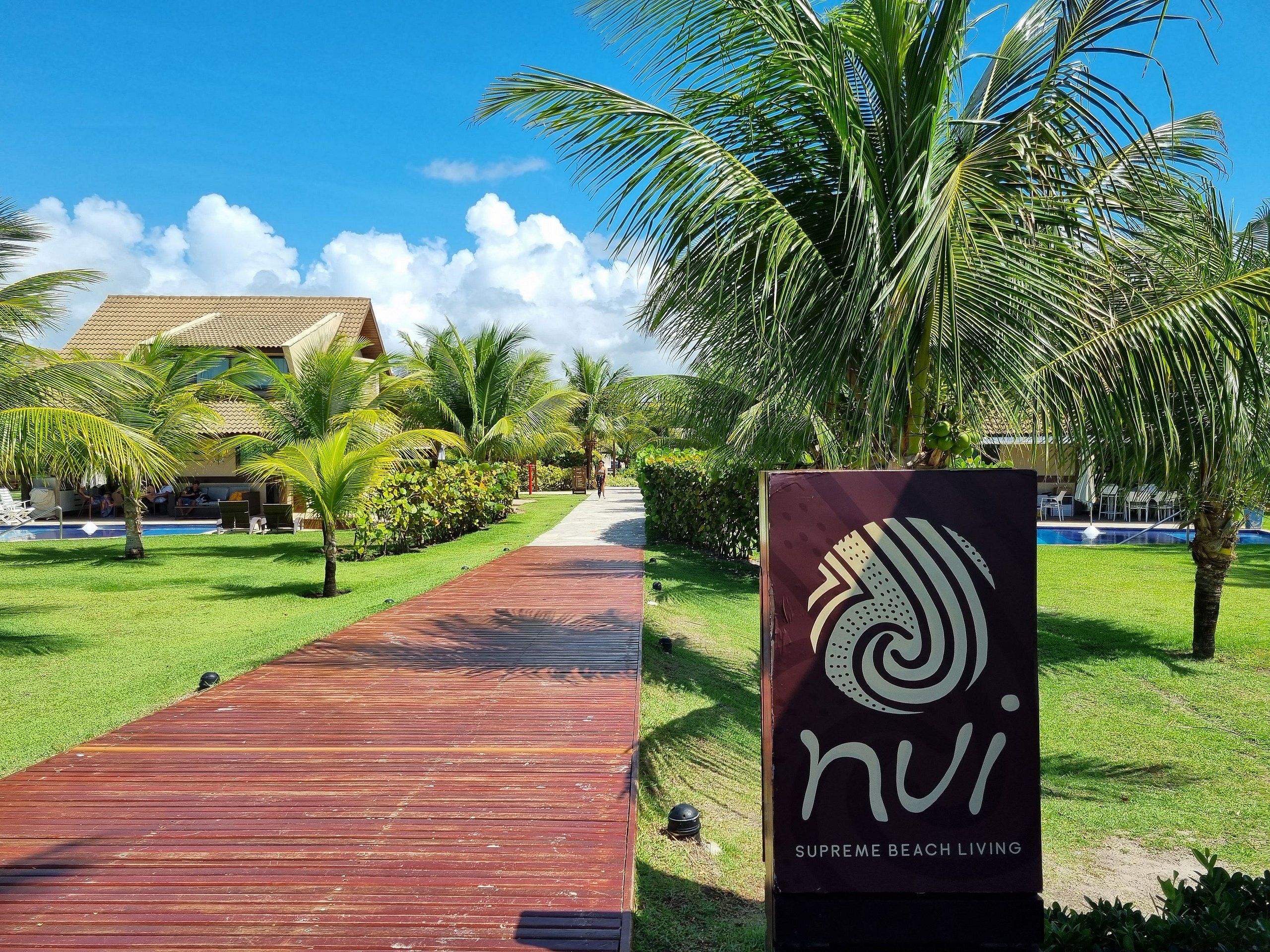 Un chemin menant à un bâtiment sur lequel on peut lire l'inscription : « nui Supreme Beach Living ».