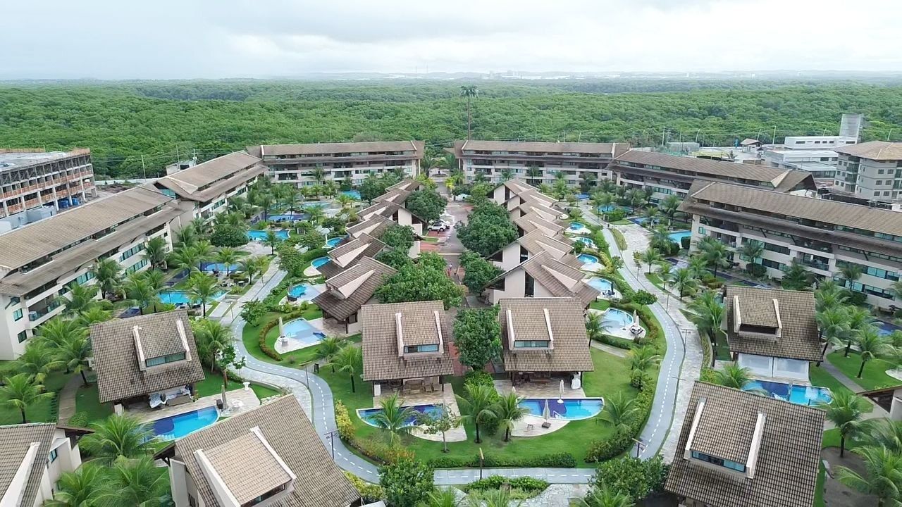 A resort with multiple buildings, swimming pools, and lush greenery.