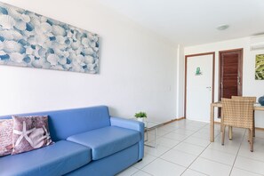 Ein Zimmer mit einem blauen Sofa, einem kleinen Tisch mit einer Pflanze und einer Tür mit einem Willkommensschild.