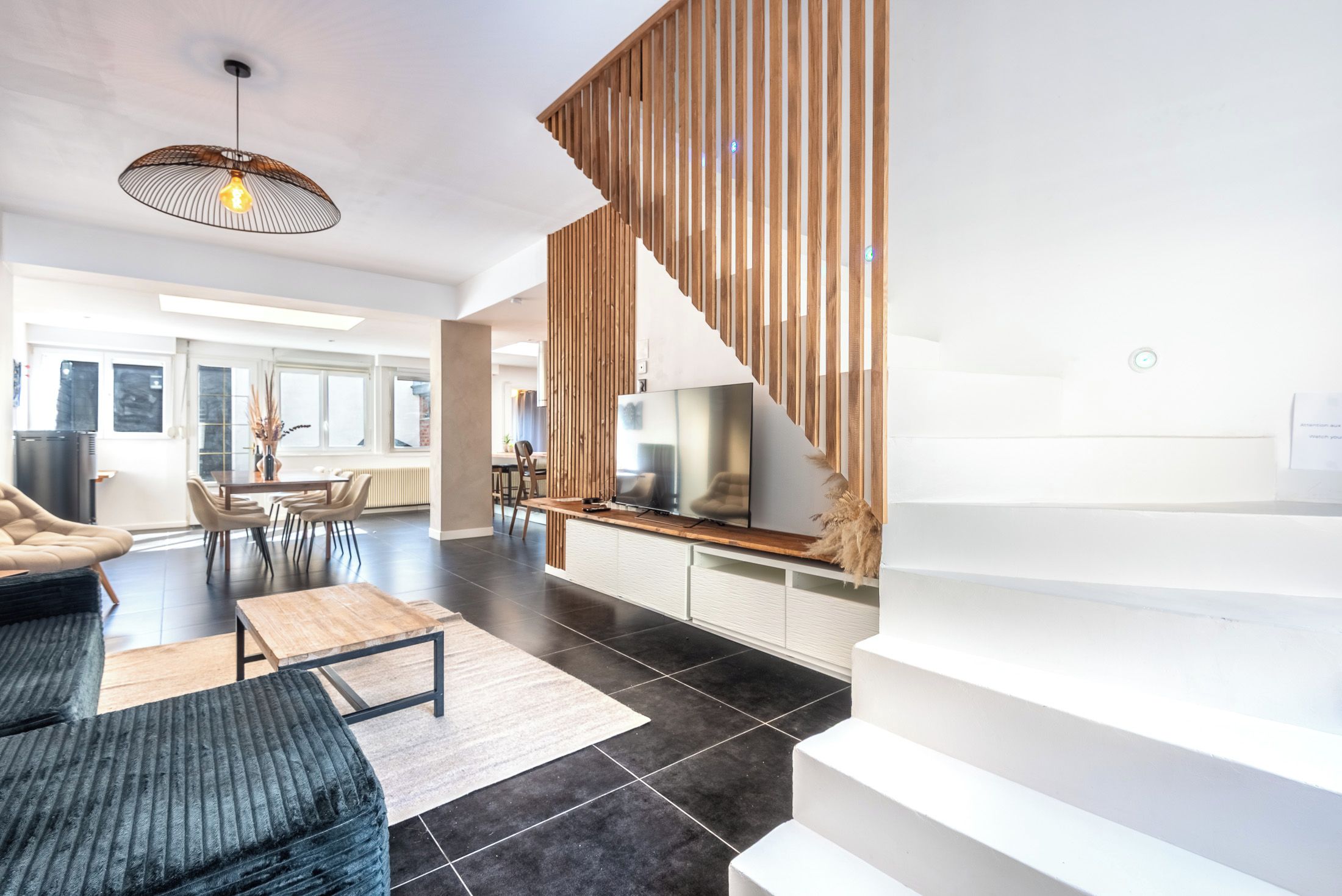 A modern living room with a sofa, coffee table, and a dining area with chairs.