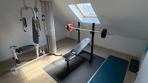 A home gym with a bench press, squat rack, and a pull-up bar. - Vrbo Property (Croix)