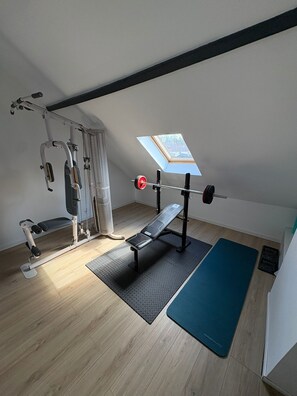 Un gimnasio en casa con una prensa de banca, una estructura para sentadillas y una barra de dominadas.
