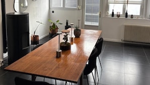 A modern dining area with a wooden table, black chairs, and potted plants. - Vrbo Property (Croix)