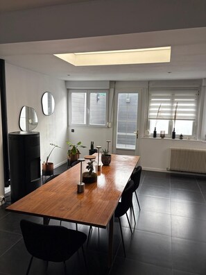 Un comedor moderno con una mesa de madera, sillas negras y plantas en macetas.