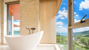 Ein modernes Badezimmer mit freistehender Badewanne, großen Fenstern und Blick auf eine grüne Landschaft.
