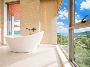 Une salle de bain moderne avec une baignoire sur pieds, de grandes fenêtres et une vue sur un paysage verdoyant.