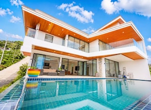 A modern two-story house with a swimming pool in front.