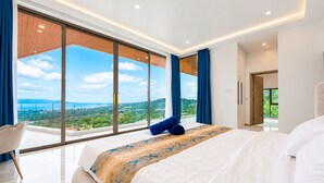 Ein modernes Schlafzimmer mit einem großen Bett, Blick auf die Landschaft und einem Balkon.