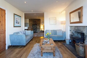 A cozy living room with two sofas, a wooden coffee table, a fireplace, and a stone wall. - Charming 3-bedroom cottage in Porthleven with spectacular harbour views
3HARB (Porthleven)