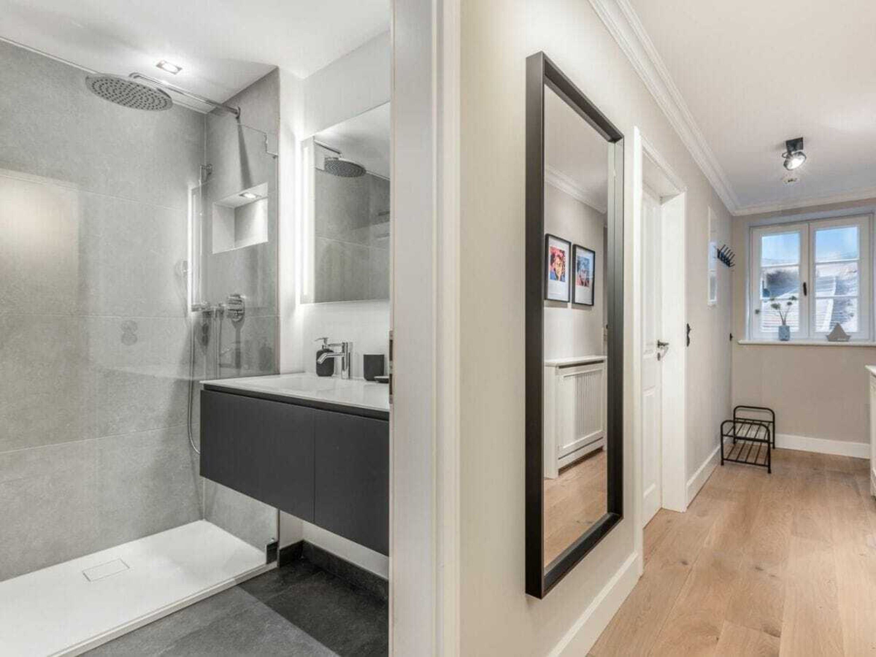 A modern bathroom with a shower, a vanity, and a large mirror.