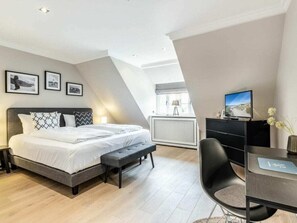 Un dormitorio moderno con cama, banca, escritorio y televisor.