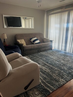 A living room with a sofa, a chair, a television, and a window with blinds. - 3-bedroom, 2-bath condo in amazing Sunrise Beach.  
This Condo sleeps 10 guests (Sunrise Beach)
