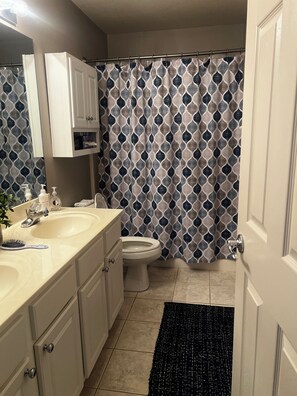 A bathroom with a double sink, toilet, and a shower curtain with a geometric pattern. - 3-bedroom, 2-bath condo in amazing Sunrise Beach.  
This Condo sleeps 10 guests (Sunrise Beach)