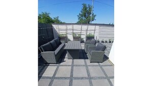 An outdoor patio area with a sofa set, a table, and potted plants. - Vrbo Property (Le Boulou)