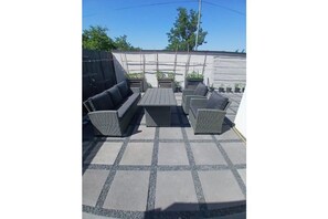 Eine Außenpatio-Terrasse mit einer Sofagarnitur, einem Tisch und Topfpflanzen.