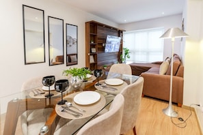 A modern dining area with a glass table, chairs, and a sofa in the background. - 90m² apartment with parking, just steps from Kennedy Park. (Miraflores)