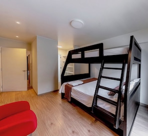 A bunk bed room with a wooden floor, a red chair, and a white door. - 90m² apartment with parking, just steps from Kennedy Park. (Miraflores)