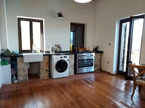 Een kleine keuken met een wasmachine, oven en spoelbak.